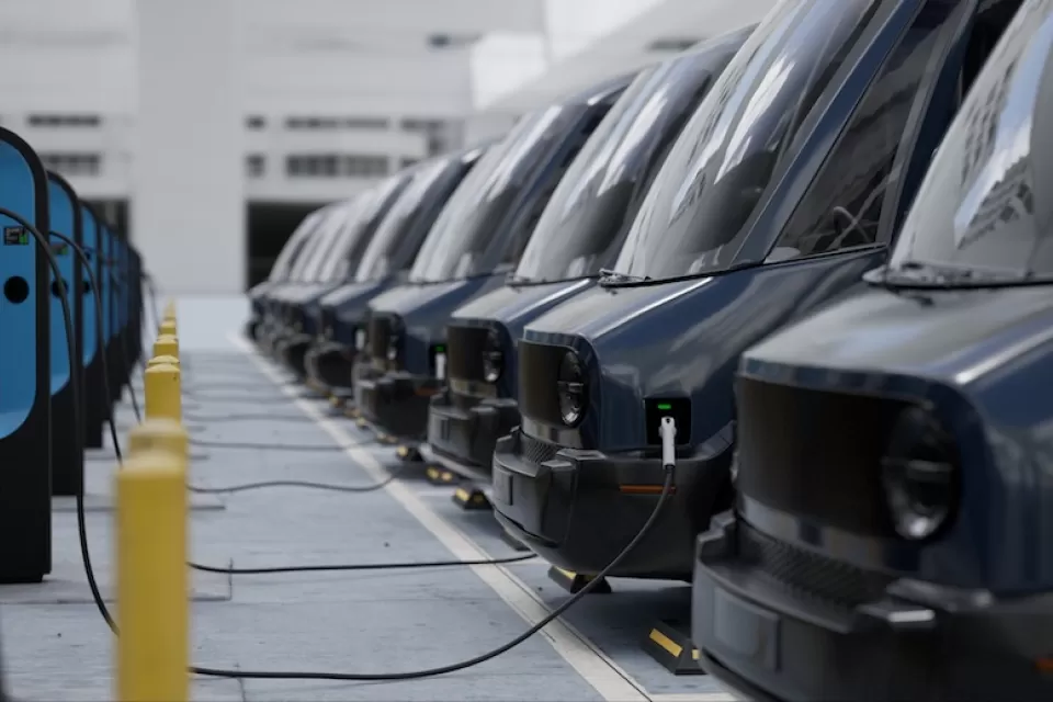 Close-up of fleet modern electric EV delivery vans being charged in covered parking garage.